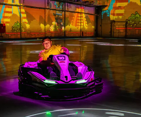 Ein Fahrer lenkt ein E-Kart über eine glänzende Indoor-Fläche.