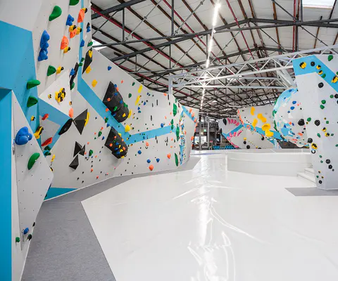 Weite Innenansicht einer hellen Boulderhalle mit viel Raum.