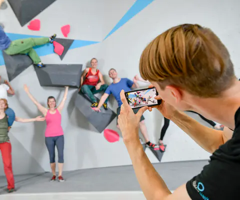 Mehrere Personen stehen an einer Kletterwand und schauen nach oben.