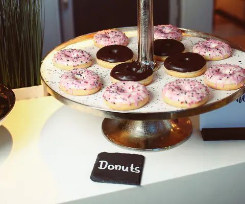 Mehrere Donuts stehen auf einer zweistöckigen Servierplatte.