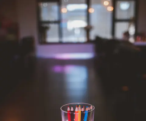 Bunte Bleistifte stehen in einem Glas auf einem Bowling-Programmblatt.