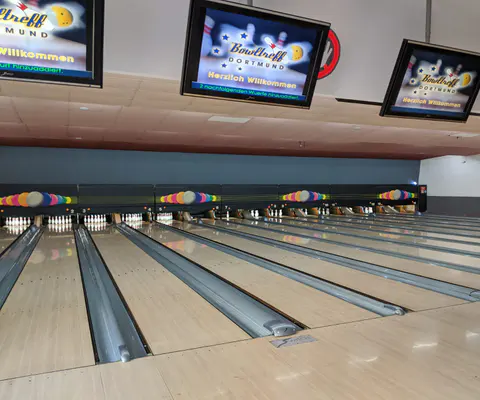 Innenraum mit mehreren Bowlingbahnen und typischer Atmosphäre einer Bowlinganlage.