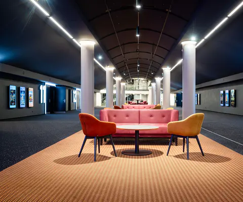 Beleuchteter Lounge- und Wartebereich mit gemütlicher Sitzgruppe im Kino.