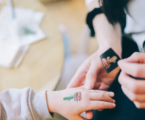Eine Hand wird mit einem kleinen Glitzertattoo auf dem Handrücken verziert.