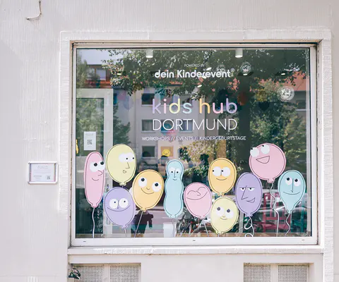 Eine Schaufensterfront mit Beschriftung und Dekoration ist von außen zu sehen.
