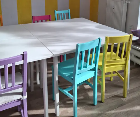 Ein farbenfroher Raum mit aufgereihten Stühlen ist für eine Feier vorbereitet.
