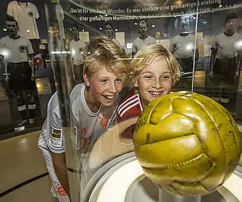 Kinder betrachten ein Exponat im Museum und tauschen sich aus.