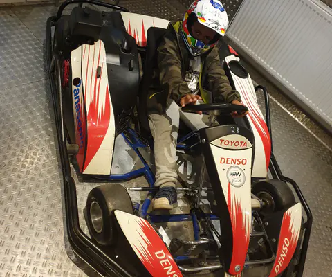 Ein Kind fährt in einem Kart auf der Rennstrecke.