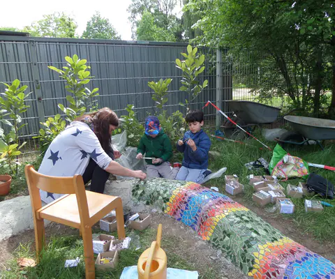 Kinder und Erwachsene arbeiten gemeinsam draußen an einer kreativen Aktivität.