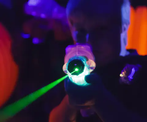 Eine Hand hält eine Laserpistole, aus der ein grüner Strahl austritt.