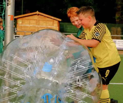 Kinder spielen Bubblesoccer in aufblasbaren Spielfeldern.