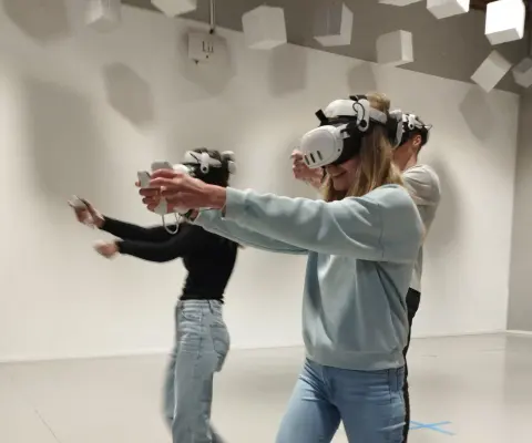 Mehrere Personen spielen in einer hellen VR-Arena.