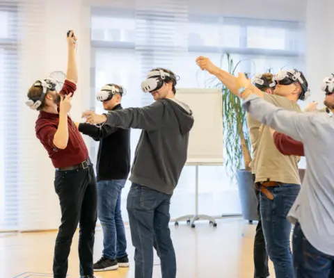 Teilnehmende mit VR-Brillen in einem hellen Raum.