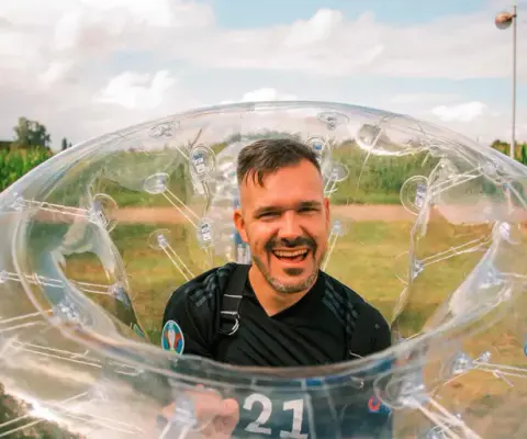 Kinder spielen Bubblesoccer auf einem Indoor-Feld.
