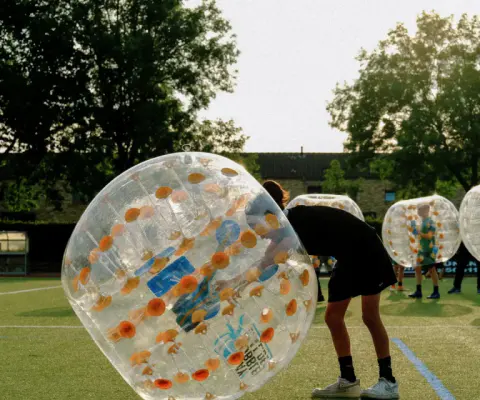 Kinder spielen im Bubble-Ball auf einer Aktionsfläche.