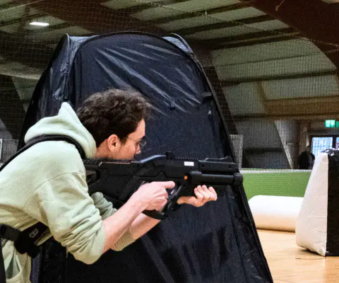 Personen spielen Lasertag in einem dunkleren Innenraum.