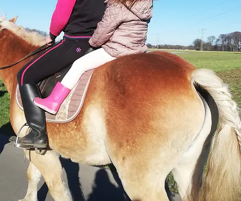 Zwei Kinder reiten gemeinsam auf einem Pony