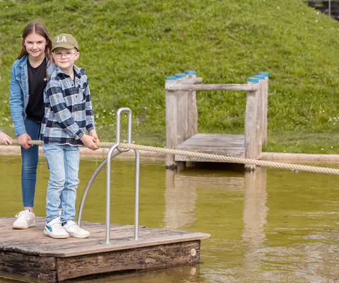 Kinder spielen auf dem Wasserspielplatz unter freiem Himmel.