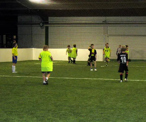 Indoor-Fußballszene in der Halle mit mehreren Spielern auf dem Spielfeld.