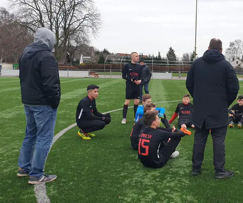 Kinder- und Jugendteam bespricht sich auf dem Sportplatz.