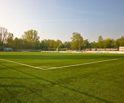 Breiter Blick auf den leeren Sportplatz mit klarer Spielfeldatmosphäre.