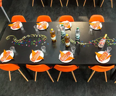 Ein gedeckter Tisch mit orangefarbenen Stühlen und Getränken von oben.