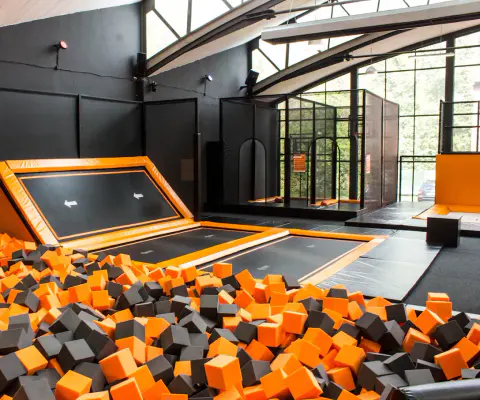Ein Trampolinbereich mit Foam Pit und orange-schwarzen Schaumstoffwürfeln.