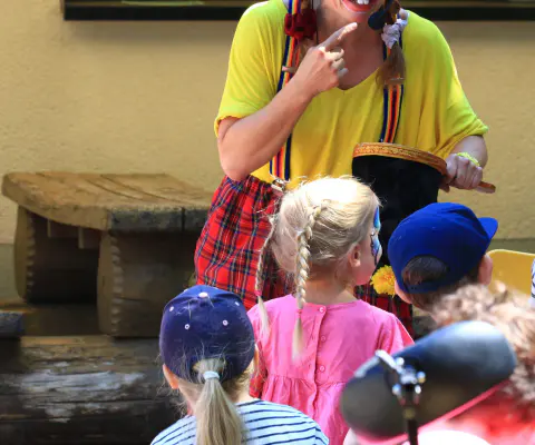 Eine Künstlerin interagiert auf einer Bühne mit Kindern.