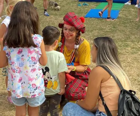 Eine Künstlerin betreut draußen Kinder in einer lebendigen Szene.