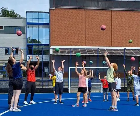 Viele Kinder trainieren gemeinsam mit einem Ball in der Halle.