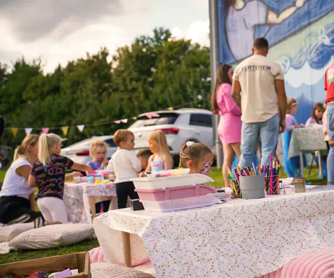 Kinder basteln im Außenbereich an einem betreuten Eventtisch.