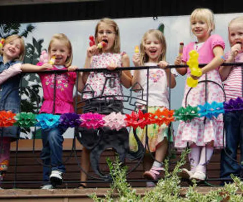 Mehrere Kinder stehen bei einer Feier zusammen im Raum.